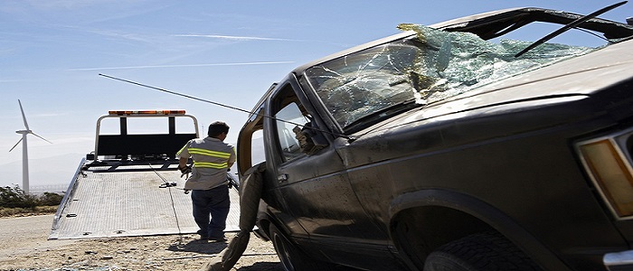 Rear view of a man preparing tow truck to carry damaged car on trailer